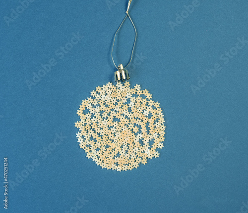 Obraz na płótnie Christmas decoration on a tree in the form of a ball of pasta on a blue paper background, top view. Conceptual photo. w salonie