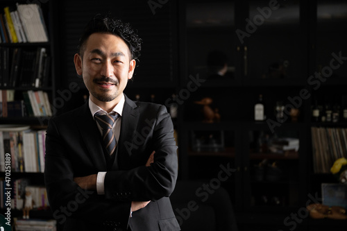 Handsome Asian (Japanese) businessman man with crossed arms smiling at the camera, copy space at right.