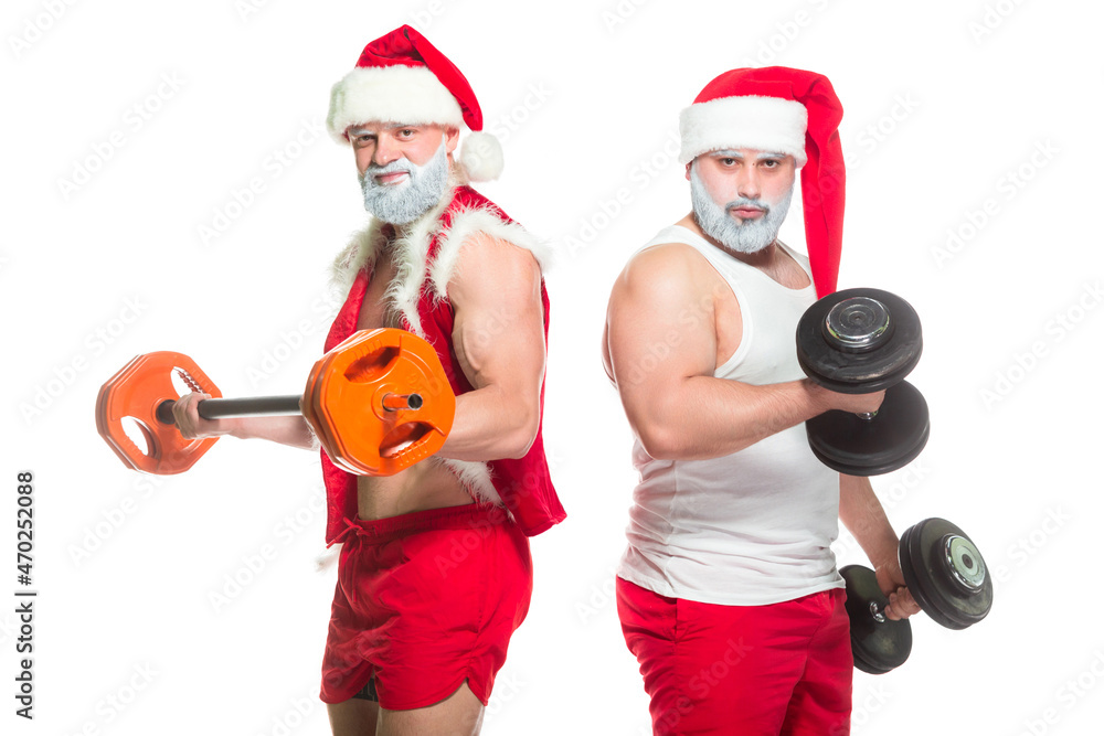 Obraz premium Christmas. Portrait of two strong muscular bearded athletes in Santa Claus costumes, training by lifting barbells isolated on white background
