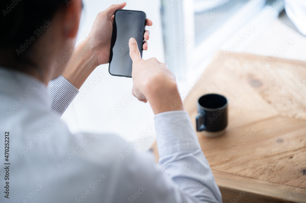 スマホでタップするビジネスマンの男性　右にコピースペースあり	