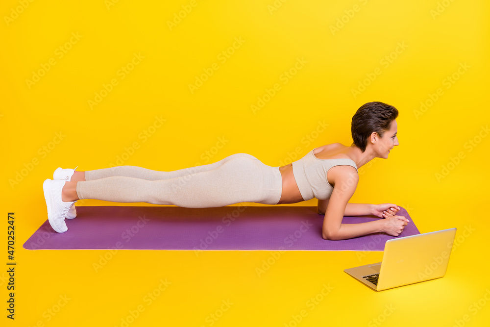 Profile side view portrait of attractive sportive cheerful girl doing physical plank isolated over bright yellow color background Profile side view portrait of attractive sportive cheerful girl doing physical plank isolated over bright yellow color background