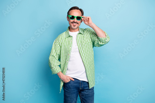 Portrait of attractive cheerful content man touching specs good mood isolated over bright blue color background © deagreez