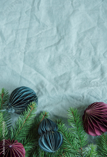 Spruce twigs with paper decorations on the green linen crumpled textile background