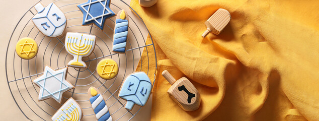 Cooling rack with tasty cookies for Hanukkah celebration and dreidels on light background