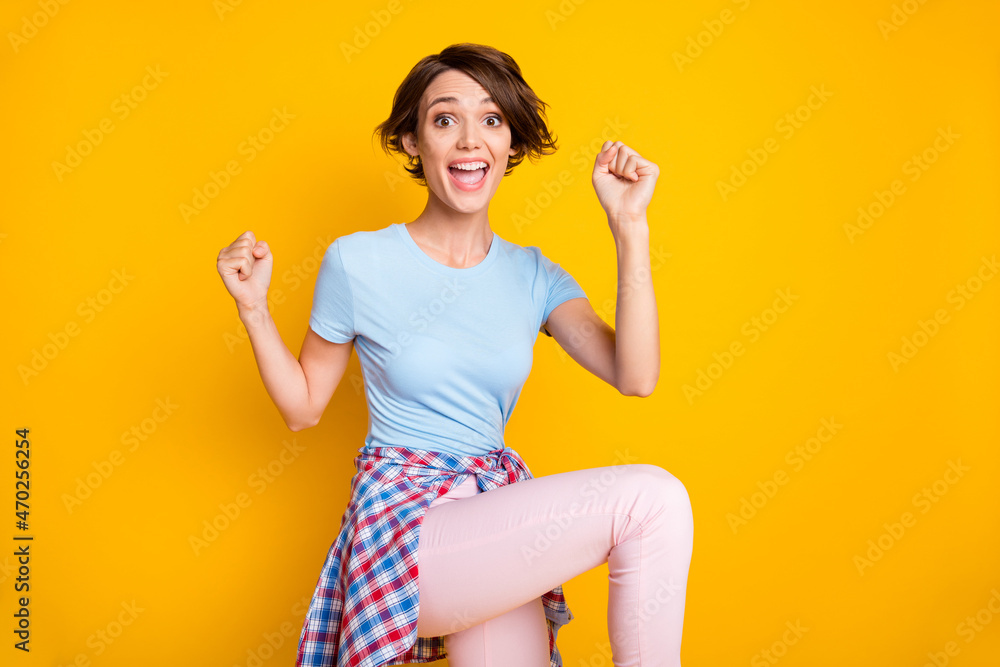Photo of young woman happy positive smile celebrate win victory success fists hands isolated over yellow color background Photo of young woman happy positive smile celebrate win victory success fists hands isolated over yellow color background