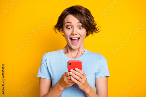 Photo of young blogger happy smile amazed surprised like repost use smartphone isolated over yellow color background