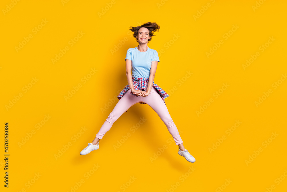Photo portrait full body view of funny woman with tight waist shirt jumping up isolated on vivid yellow colored background