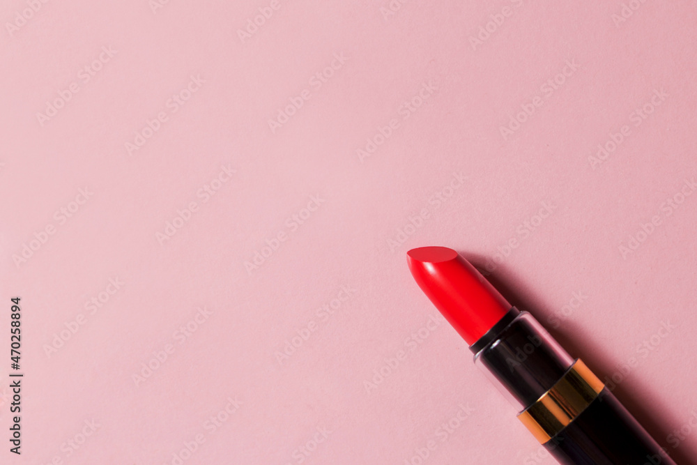 Fototapeta premium Red lipstick in a black package on a pink background with space for text. Cosmetics top view