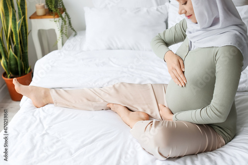 Pregnant Muslim woman relaxing in bedroom