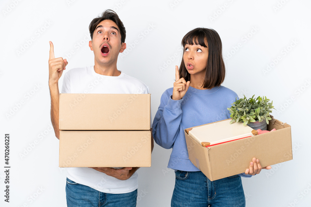 Young couple making a move while picking up a box full of things isolated on white background thinking an idea pointing the finger up Young couple making a move while picking up a box full of things isolated on white background thinking an idea pointing the finger up