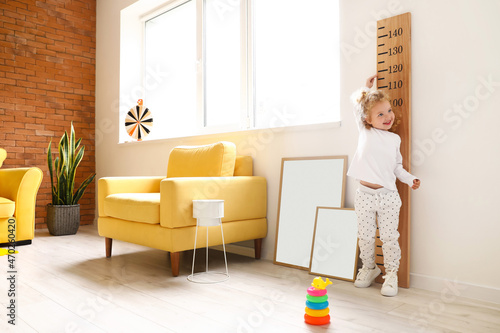 Cute baby girl measuring he...
