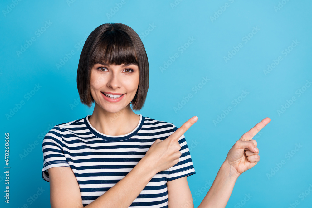Photo of charming young happy positive woman point fingers empty space sale isolated on blue color background Photo of charming young happy positive woman point fingers empty space sale isolated on blue color background