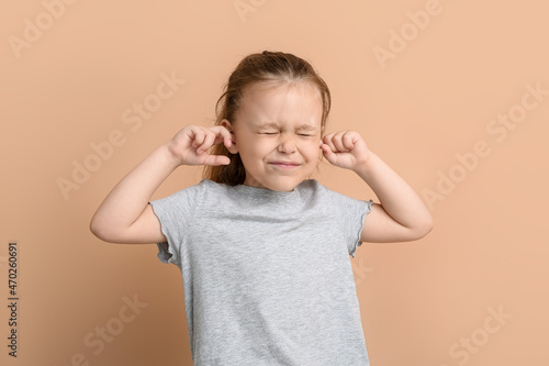 Bilde på lerret Portrait of pretty little girl plugging ears on color background
