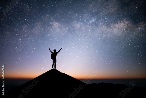 Young traveler and backpacker standing and open arm watched the star and milky way alone on top of the mountain. He enjoyed traveling and was successful when he reached the summit.