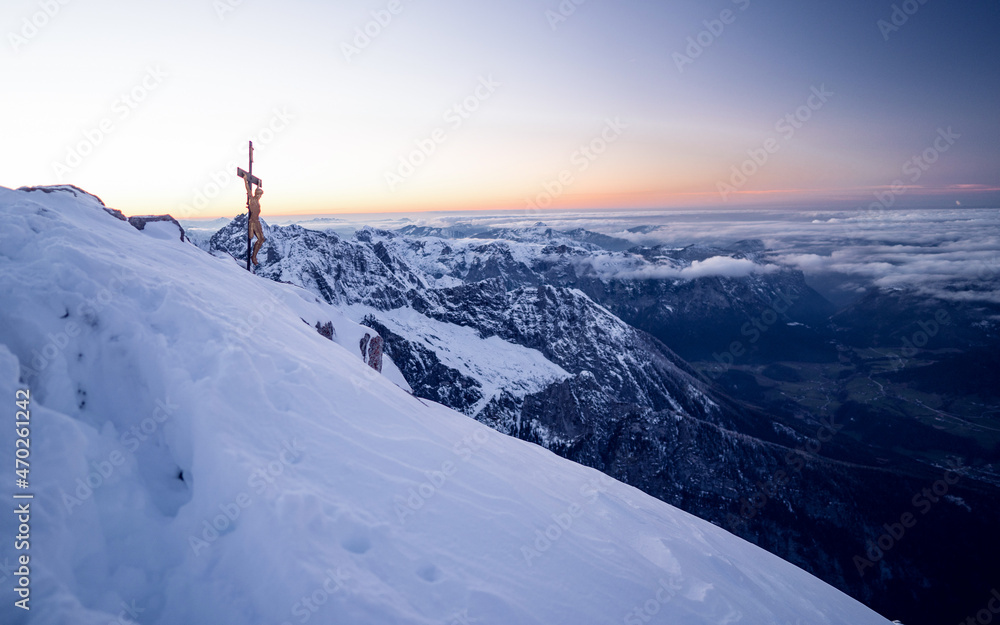 Peak with a wooden cross Watzmann mountain at sun rise in winter with a lot of snow, Berchtesgaden national park, Bavaria, Germany
