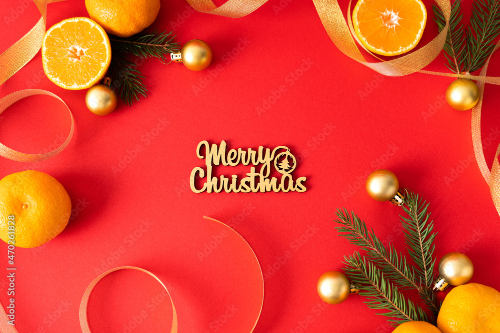Naklejka premium The inscription merry christmas on a red background is decorated with Christmas decorations, ribbons, tangerines and coniferous branches. Christmas card.