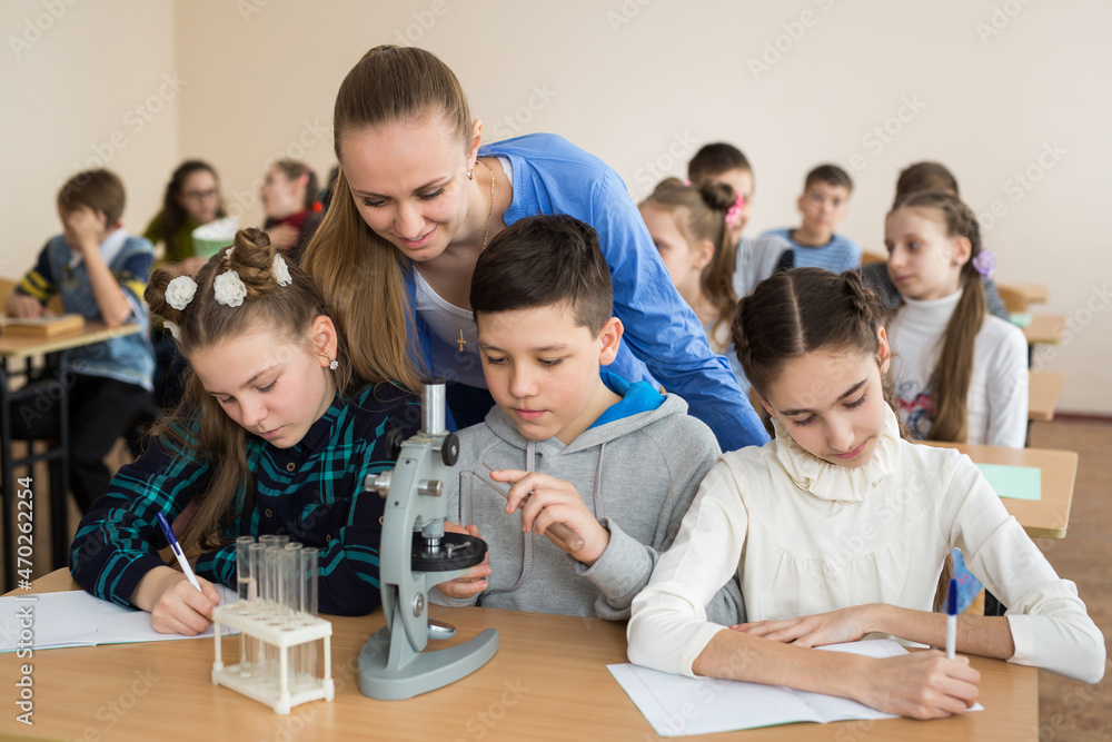 Students using science beakers and a microscope at the elementary school Students using science beakers and a microscope at the elementary school