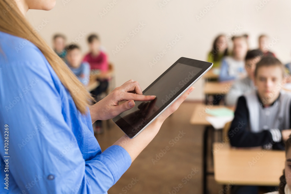Teacher asking her students a question at the elementary school with tablet computer Teacher asking her students a question at the elementary school with tablet computer