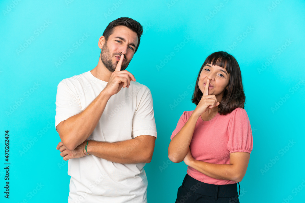Fototapeta premium Young couple isolated on blue background showing a sign of closing mouth and silence gesture