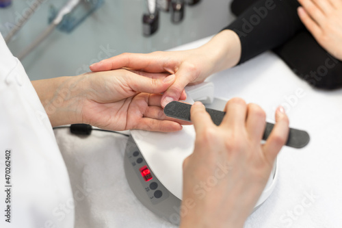 Manicure. Close-up Of Female Hands Filing Nails With Nail File In Beauty Salon. Closeup Of Beautiful Woman Hand With Natural Healthy Nails Polishing Nails With Buffer  Nail Care Tool