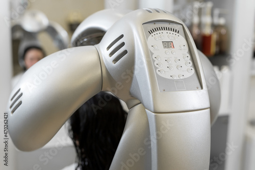 Close-up of professional hair dryer dries young girl's hair. Portrait of a girl in a beauty salon. The procedure of moisturizing hair mask in a professional hair salon