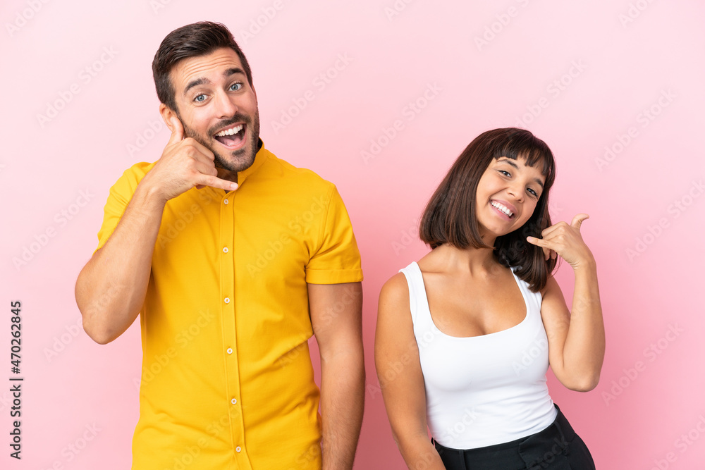 Young couple isolated on pink background making phone gesture. Call me back sign Young couple isolated on pink background making phone gesture. Call me back sign
