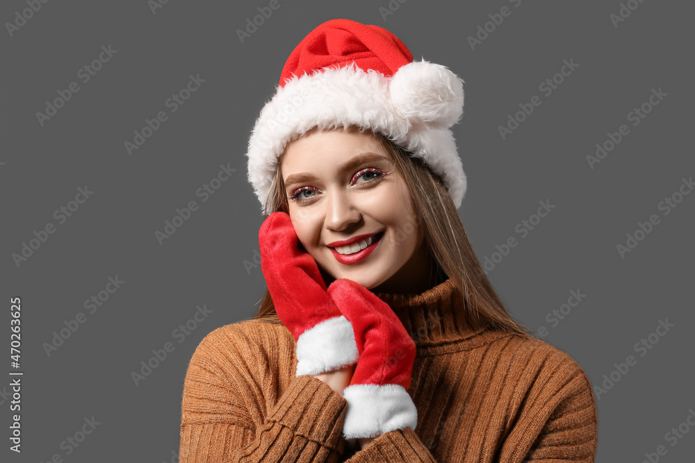 Beautiful woman in Santa hat and with mittens on dark background Beautiful woman in Santa hat and with mittens on dark background