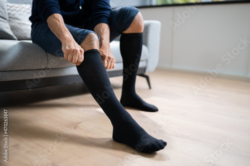 Foto Man Putting On Medical Compression Stockings