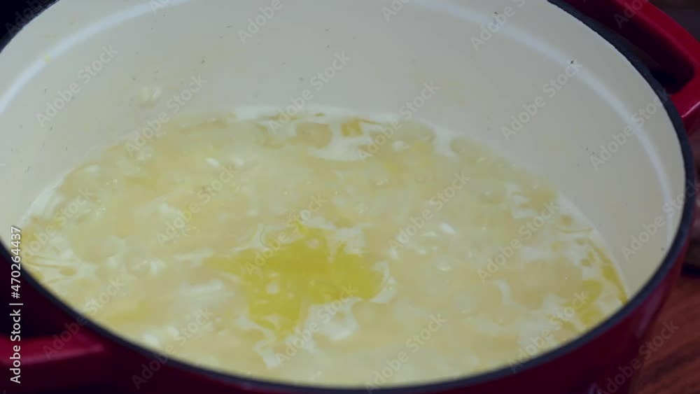 Preparing white rice. Stir the boiling rice from the pan with a wooden spoon and add a glass of white wine. Preparing white rice. Stir the boiling rice from the pan with a wooden spoon and add a glass of white wine.