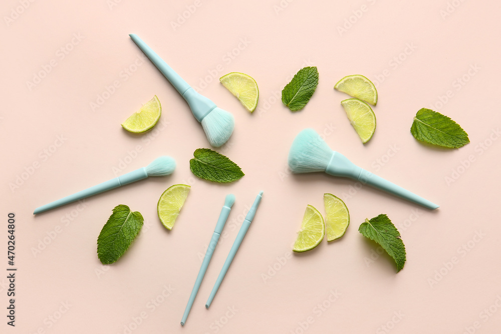 Stylish makeup brushes with lime and mint on color background