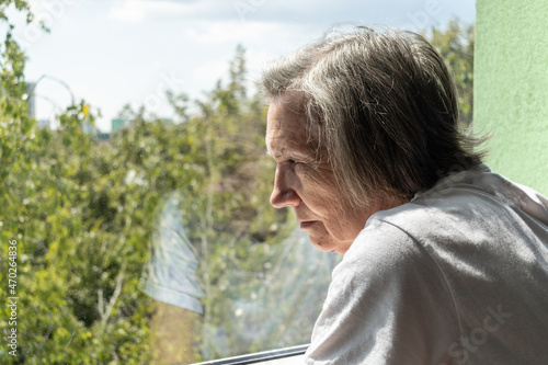 sad senior woman female alone home closeup depressed coronavirus isolation widower unhappy abandoned window