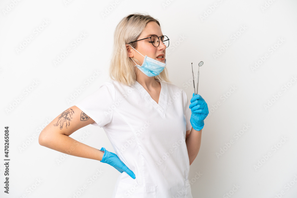 Dentist caucasian woman holding tools isolated on white background suffering from backache for having made an effort Dentist caucasian woman holding tools isolated on white background suffering from backache for having made an effort