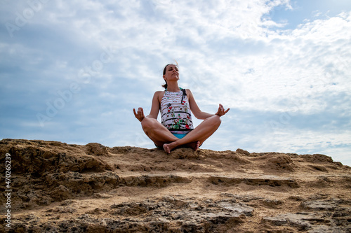 Woman meditating in lotus pose  sitting on the sandy rock  relaxing and enjoying in silence and peace. 