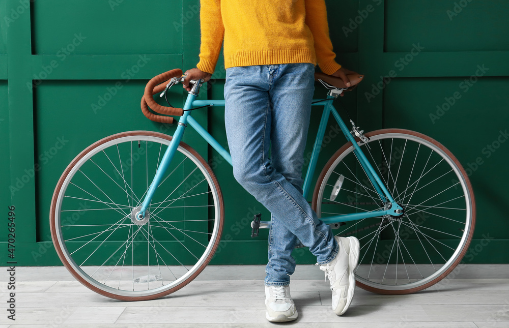 Fototapeta premium African-American teenage boy with bicycle near green wall