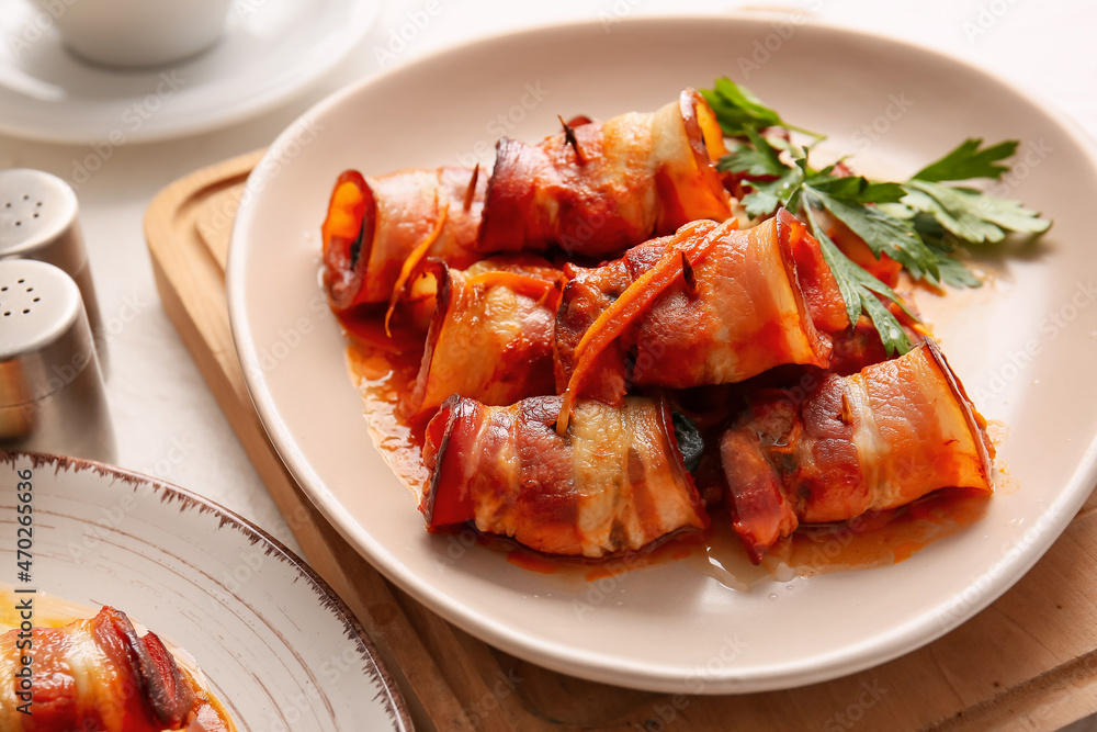 Plate with delicious prunes baked in crispy bacon and gravy on wooden board, closeup Plate with delicious prunes baked in crispy bacon and gravy on wooden board, closeup