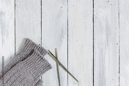 Handarbeit: gestrickte Socken mit Stricknadeln auf weißem Holztisch