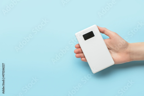 Woman holding modern power bank on blue background
