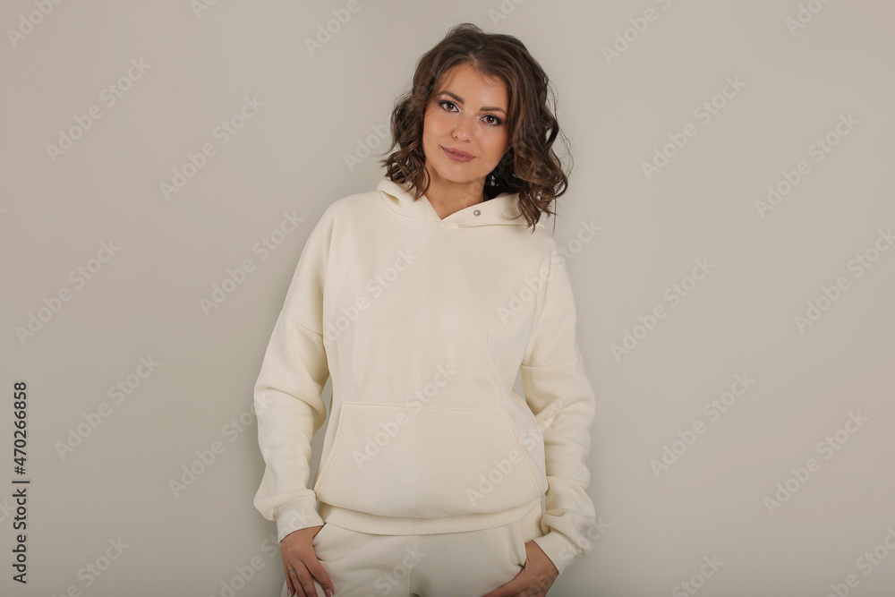 young beautiful brown-haired girl in a warm milk-colored tracksuit white background portrait young beautiful brown-haired girl in a warm milk-colored tracksuit white background portrait