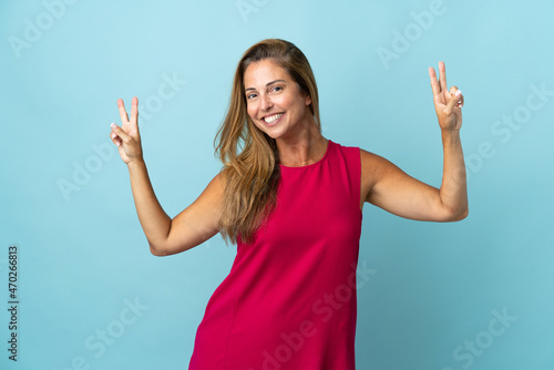 Middle age brazilian woman isolated on blue background showing victory sign with both hands