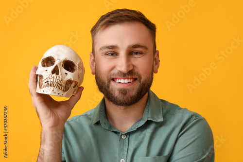 Handsome man with human skull on yellow background © Pixel-Shot