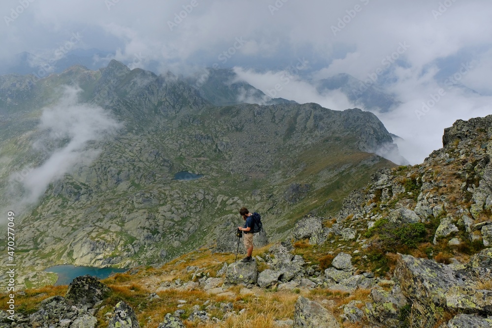 Beautiful mountain view above clouds around peak Djeravica (Gjerovica) - highest peak of Kosovo. Silhouette of lonely tourist with backpack on trail. Albanian Alps, Peaks of Balkans