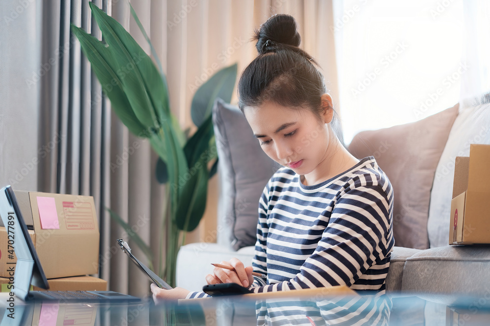 Asian small business owner checking order by smartphone at home office. Business retail market and online sell marketing delivery, SME e-commerce concept. Asian small business owner checking order by smartphone at home office. Business retail market and online sell marketing delivery, SME e-commerce concept.