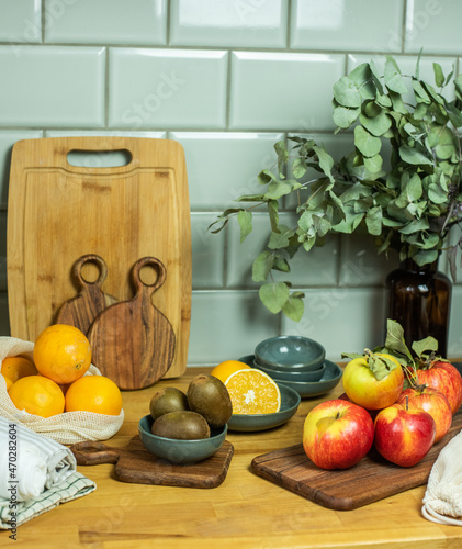 Auswahl an Obst auf Frettchen, in verschiedenen Schalen und Tellern auf Holzuntergrund mit Fliesenspiegel. Gesunde, vitaminreiche, vegane Ernährung, ethisch nachhaltiger Lebensstil, umweltfreundlich, 