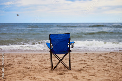 Fototapeta Naklejka Na Ścianę i Meble -  Blue folding chair back on sea beach, without people, beach holiday alone, loneliness