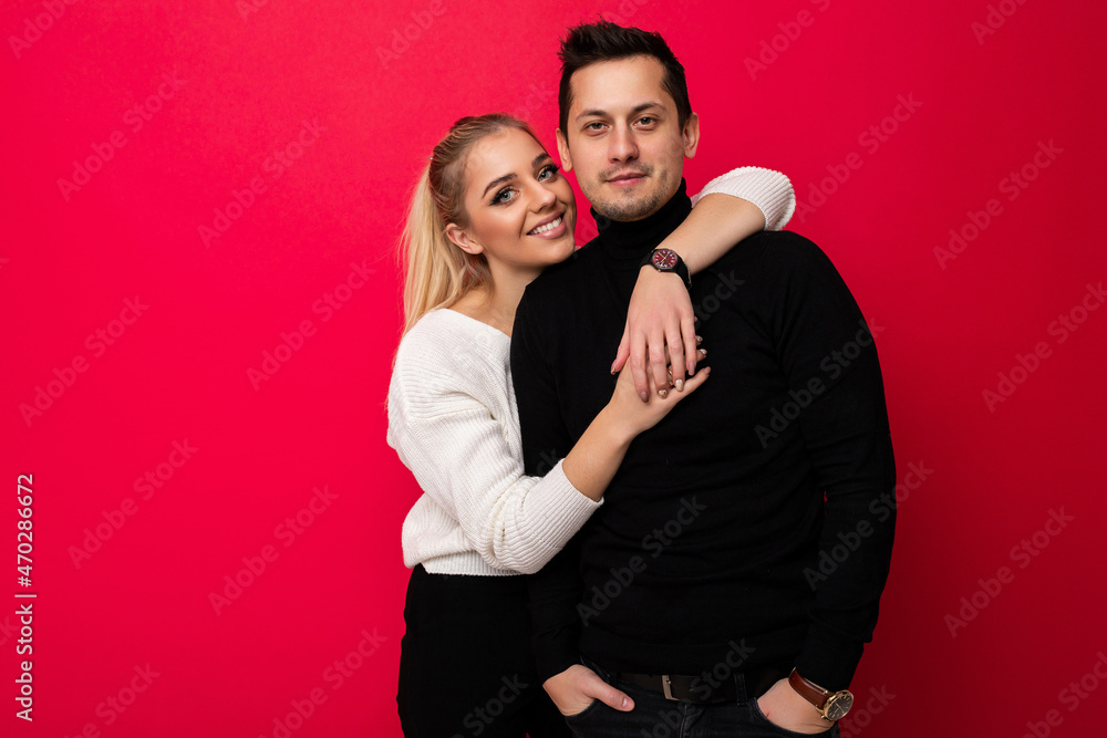 Photo of a beautiful pretty amazing positive smiling happy young blonde woman with makeup and ponytail in a stylish white knitted sweater and black pants and an adult brunet man with stubble in a Photo of a beautiful pretty amazing positive smiling happy young blonde woman with makeup and ponytail in a stylish white knitted sweater and black pants and an adult brunet man with stubble in a