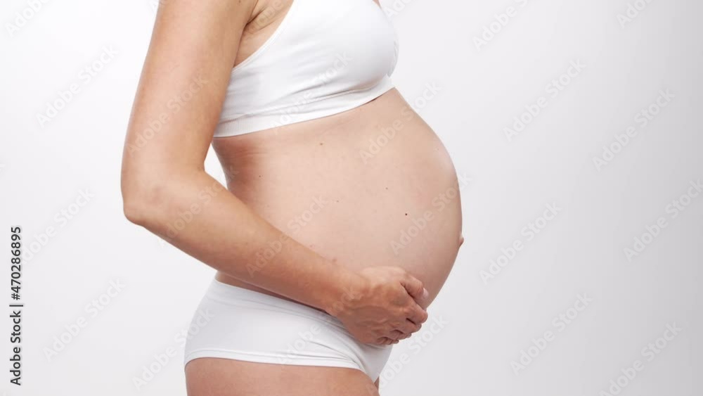 Young, happy and healthy pregnant woman on white background. Studio video. Baby expectation, pregnancy and motherhood concept.