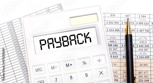 Fotografie On the desktop there are reports, a white calculator with the text PAYBACK on the scoreboard and a pen