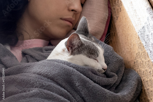 Sleeping with the female cat. A woman sleeping in a hammock with her white female cat wrapped in a blanket. Cat lover. Animal lover. Lifestyle.