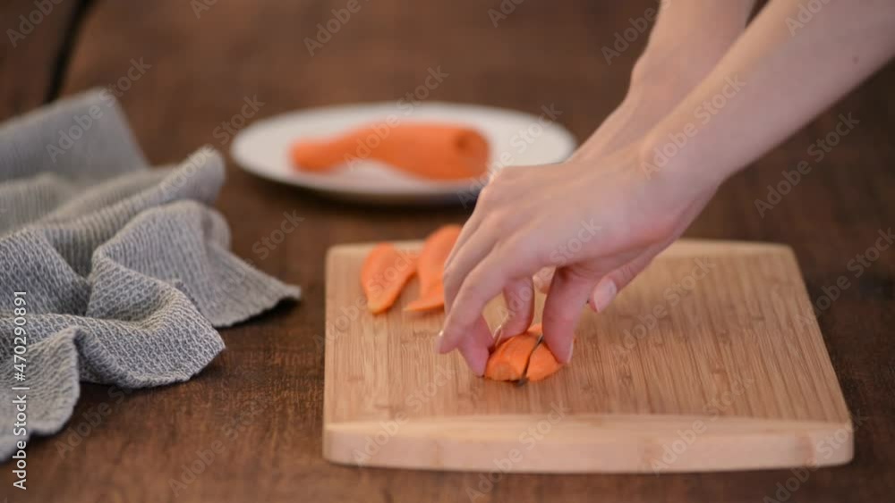 Female chef chopping carrots on a wooden board. Female chef chopping carrots on a wooden board.