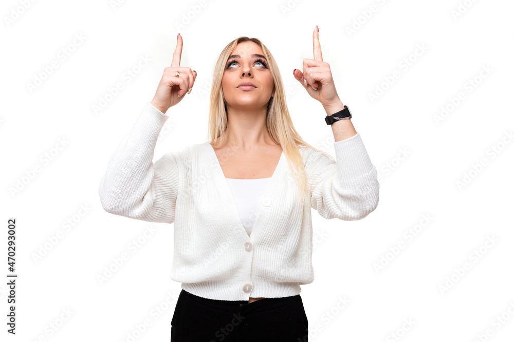 Photo of a beautiful attractive pretty amazing charming young blonde woman with makeup in a stylish white knitted sweater and black pants shows fingers up isolated on a white background with empty Photo of a beautiful attractive pretty amazing charming young blonde woman with makeup in a stylish white knitted sweater and black pants shows fingers up isolated on a white background with empty